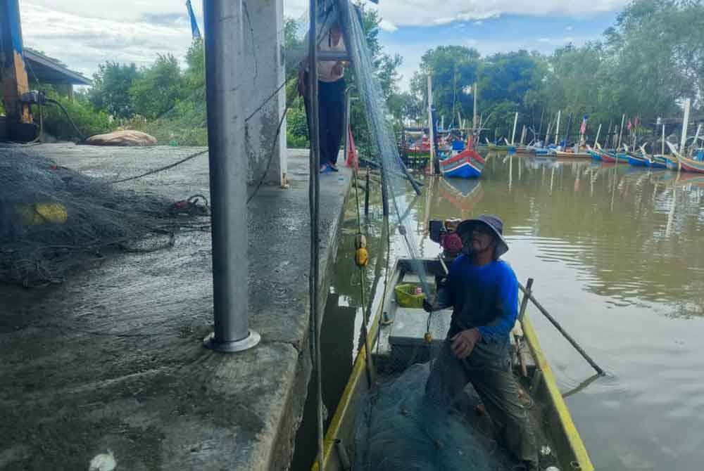Seorang nelayan membersihkan pukat selepas pulang dari laut di Jeti Pendaratan Ikan Kampung Seberang Kota, Kuala Kedah.