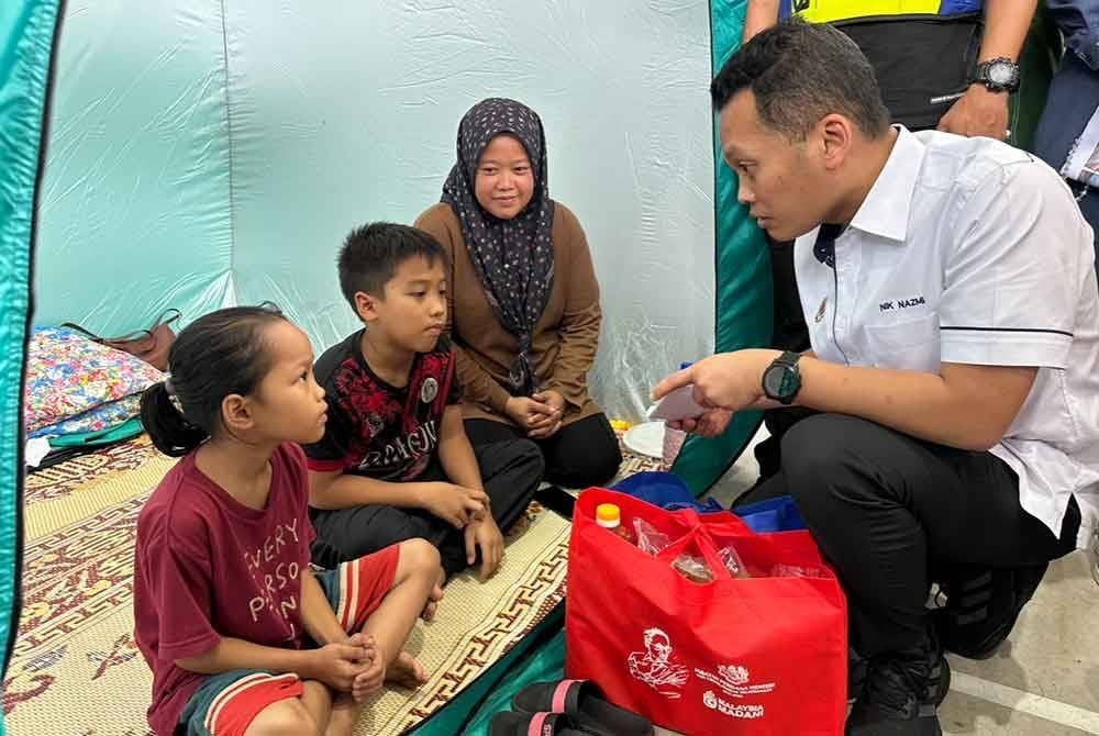 Nik Nazmi (kanan) beramah mesra dengan mangsa banjir.