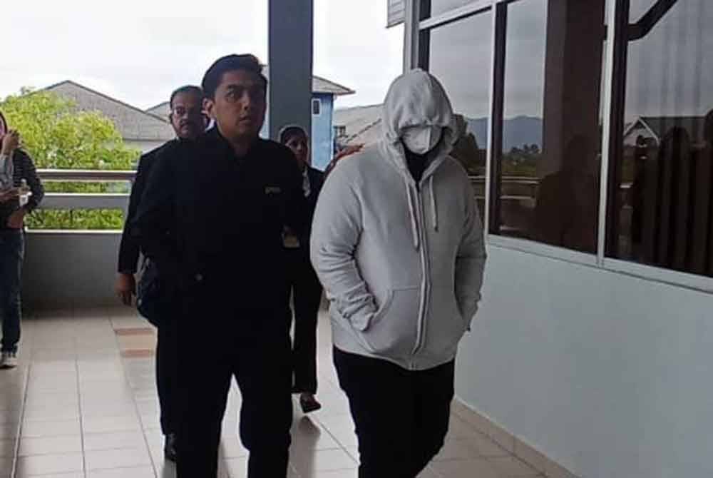 Pegawai SPRM membawa tertuduh ketika hadir di Mahkamah Sesyen atas pertuduhan menerima rasuah.