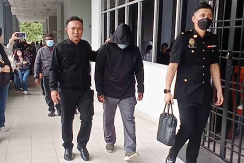 Pegawai SPRM membawa tertuduh ketika hadir di Mahkamah Sesyen atas pertuduhan menerima rasuah.