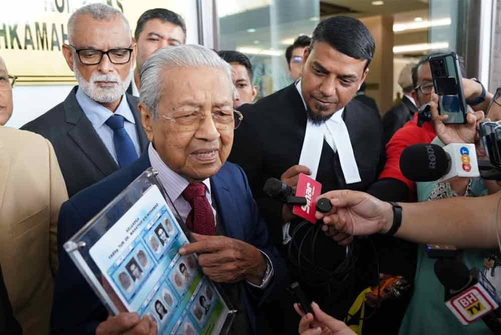 Dr Mahathir menunjukkan salinan kad pengenalan lama miliknya, sebagai bukti di Mahkamah Tinggi pada Khamis, bagi mengesahkan namanya bukan `Mahathir anak lelaki Iskandar Kutty'.