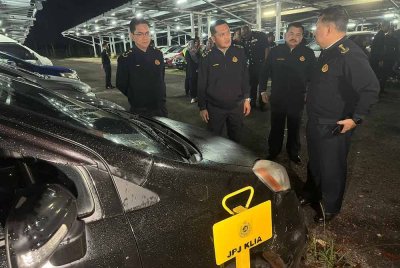 Jazmanie (dua dari kiri) melihat antara kenderaan yang disita dipercayai terlibat dengan kegiatan kereta sewa haram atau 'ulat' di KLIA.