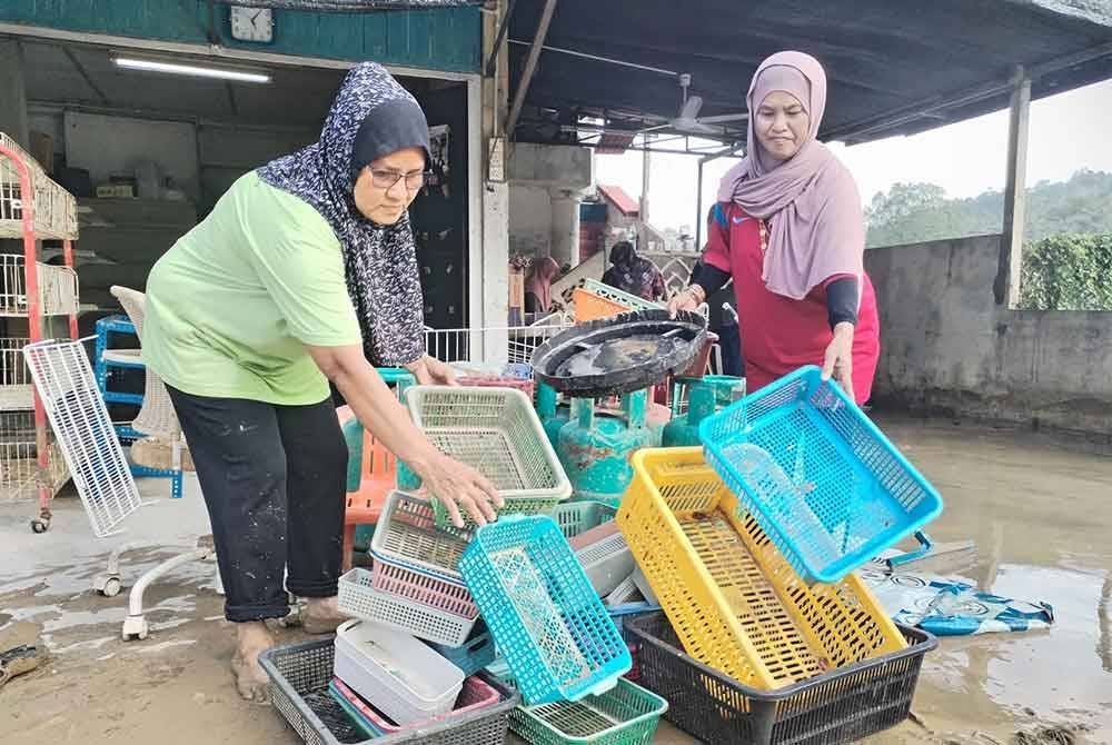 Perkhidmatan mencuci rumah mangsa banjir menjadi sumber pendapatan sampingan buat Azmah (kiri) susulan tidak dapat menoreh getah ketika musim hujan.