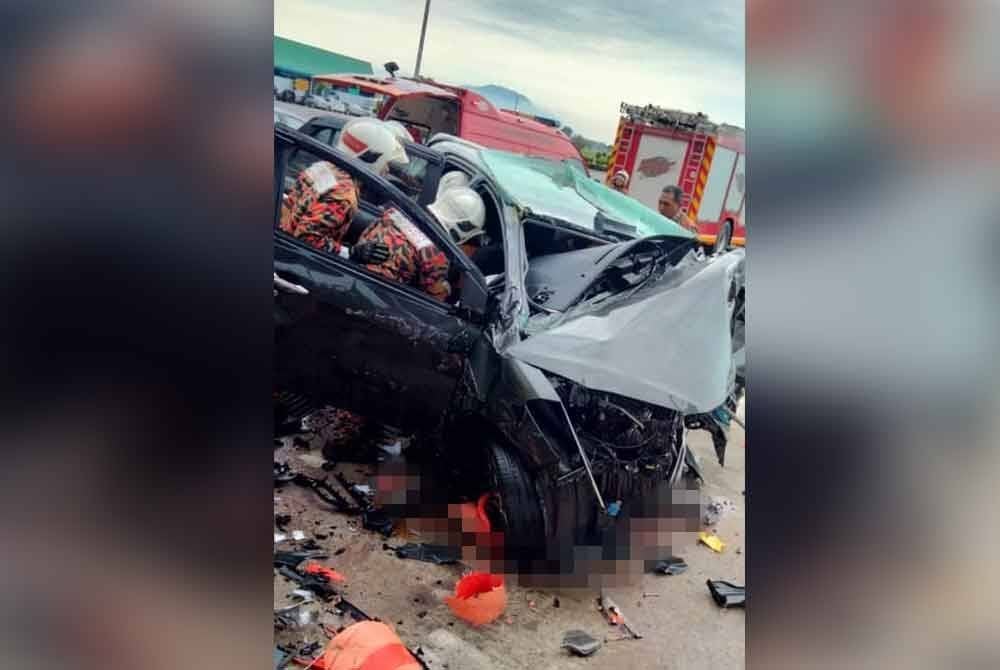 Anggota bomba sedang mengeluarkan mayat mangsa yang tersepit.