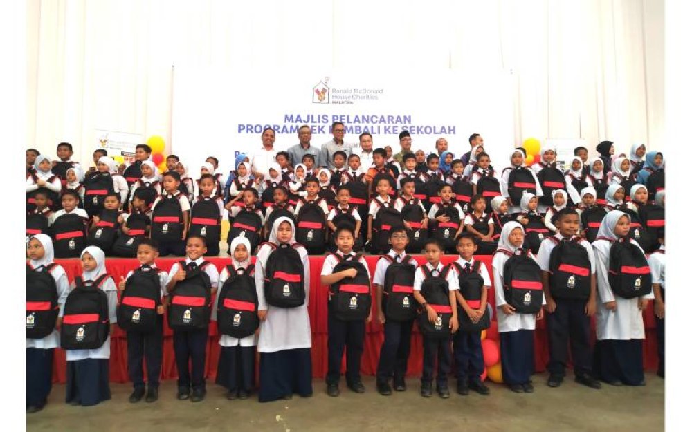 Nasri dan Azmir bersama murid-murid yang menerima sumbangan Pek Kembali ke Sekolah di Dewan Semai Bakti Felda Pasir Besar, Kampung Pasir Besar, Tampin, barubaru ini.