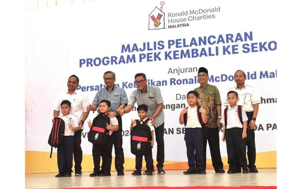 Dua dari kiri: Pengurus Besar RMHC Malaysia, Nasri Nordin dan Presiden RMHC Malaysia, Datuk Azmir Jaafar menyampaikan sumbangan Pek Kembali ke Sekolah kepada murid- murid dari daerah Tampin.
