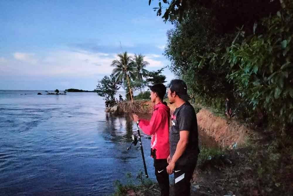 Muhd Shah Ishraf (kiri) bersama Shahniezamyusry mencuba nasib memancing ikan patin