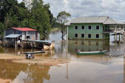Penduduk setempat menggunakan bot untuk melakukan kegiatan harian berikutan kawasan kediaman mereka masih digenangi banjir walaupun air mulai surut ketika tinjauan di Kampung Lachang, Rantau Panjang pada Sabtu. Foto Bernama