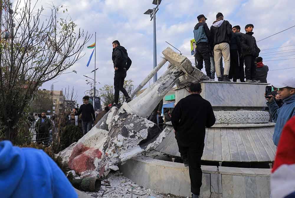 Penduduk Syria menumbangkan patung bekas Presiden Hafez al-Assad semasa meraikan rampasan kuasa di Damsyik. - Agensi