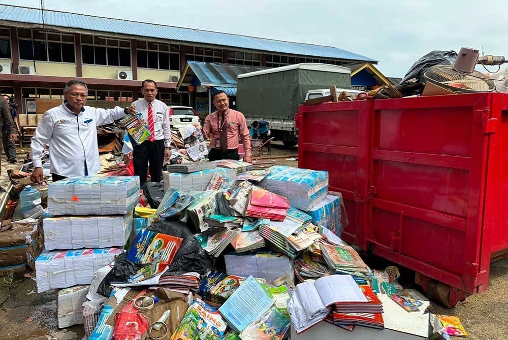 Mohammad Razuki (kiri) menunjukkan buku-buku dari kedai koperasi sekolah yang terkena banjir.
