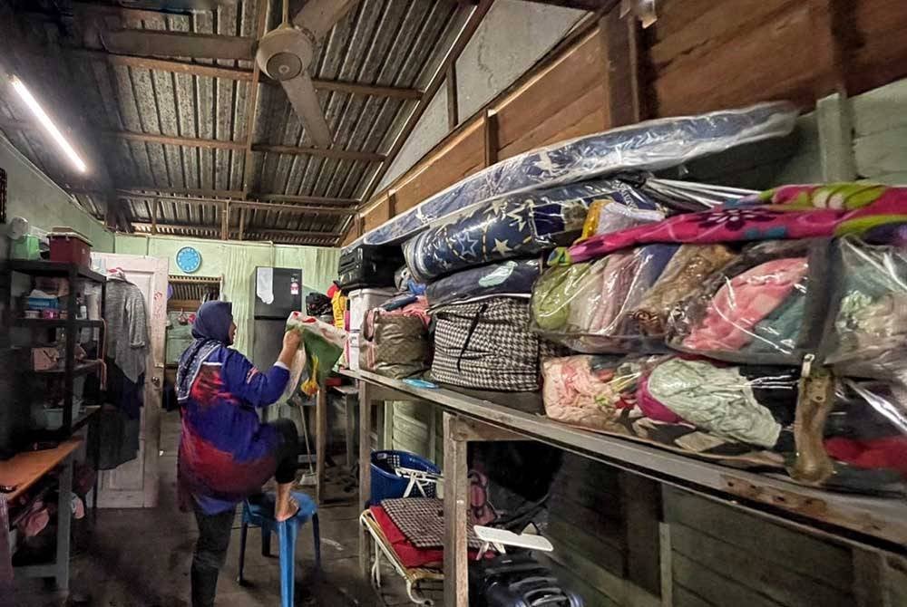 Nurul Hanim sedang menaikkan barangan rumah diatas tempat tinggi yang dibina di dalam rumah bagi mengelak ditenggelami banjir ketika ditemui Sinar Harian pada Isnin.