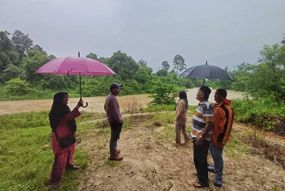 Mohamad Amerudin (kanan) bersama ahli jawatankuasa kampung melihat keadaan Sungai Belat.