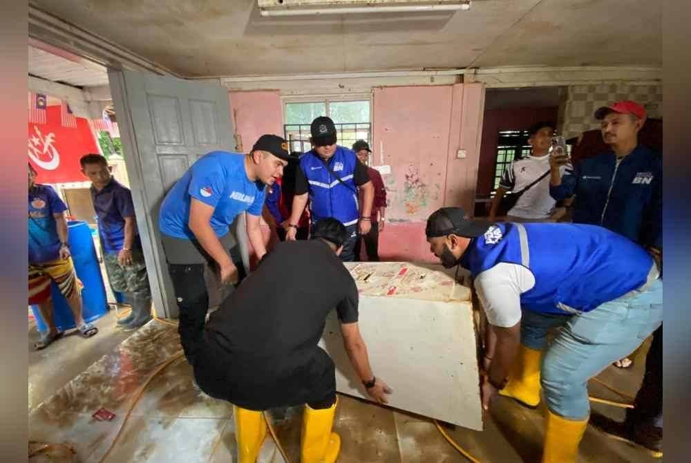 Muhamad Akmal (kiri) turun padang bergotong-royong membersihkan Tabika Kemas Harmoni di Kampung Serongga, Pasir Mas.