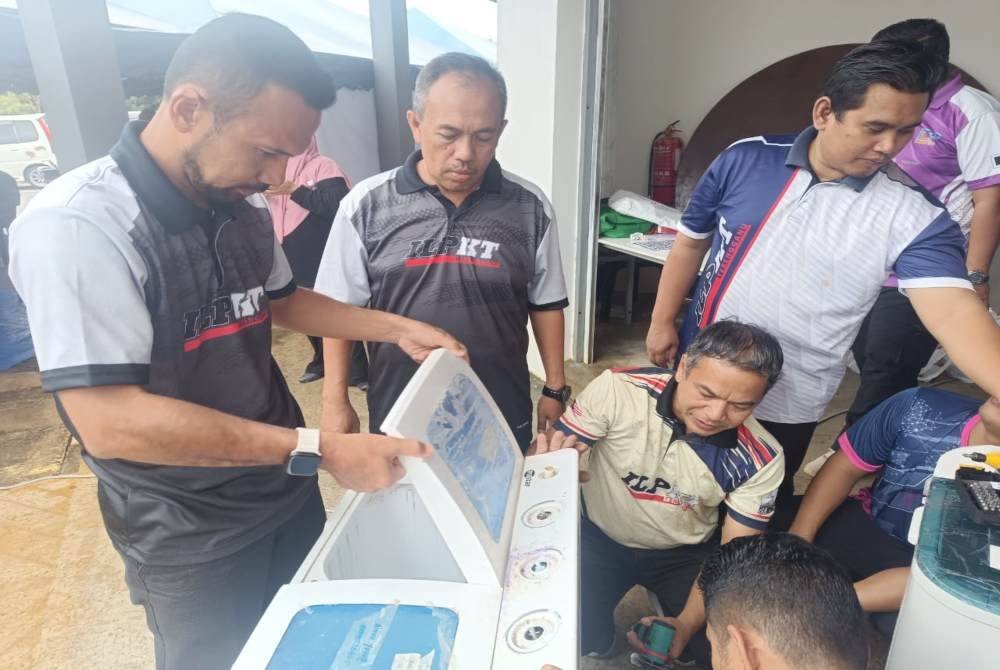 Muhammad Nasir (tengah) melihat kakitangan dan pelajar ILP baiki mesin basuh.