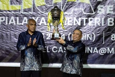 Saarani (kanan) menjulang piala pusingan yang menjadi rebutan pasukan bertanding sambil disaksikan Khairudin.