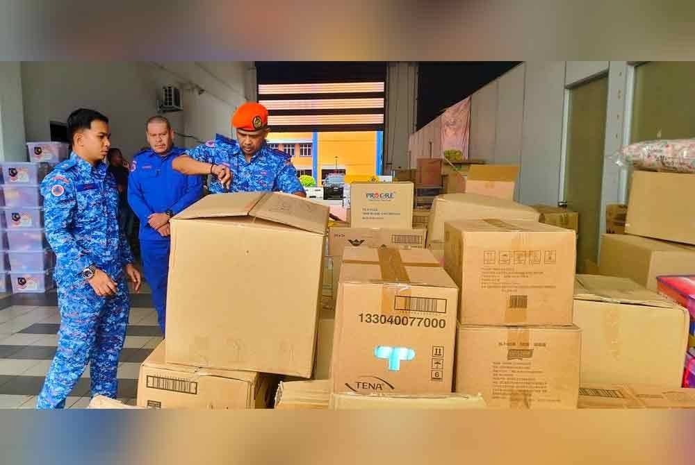 Che Adam menunjukkan antara barangan sumbangan yang diterima dan dikumpulkan di pusat pengumpulan di Ibu Pejabat APM Pahang di Kuantan.