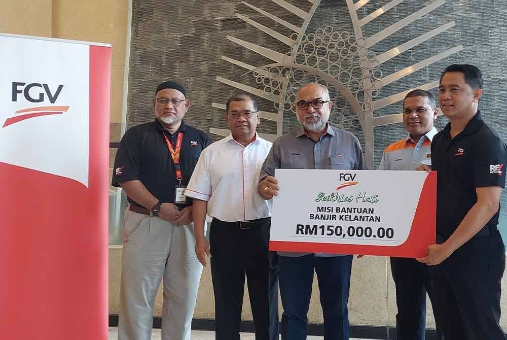 Rastam (tiga dari kiri) menyampaikan replika cek bernilai RM150,000 sempena Misi Bantuan Banjir Kelantan kepada Shaharizan (dua dari kanan) ketika Majlis Pelepasan Konvoi Bantuan Banjir FGV Holdings Berhad Ke Kelantan di Wisma FGV pada Rabu.