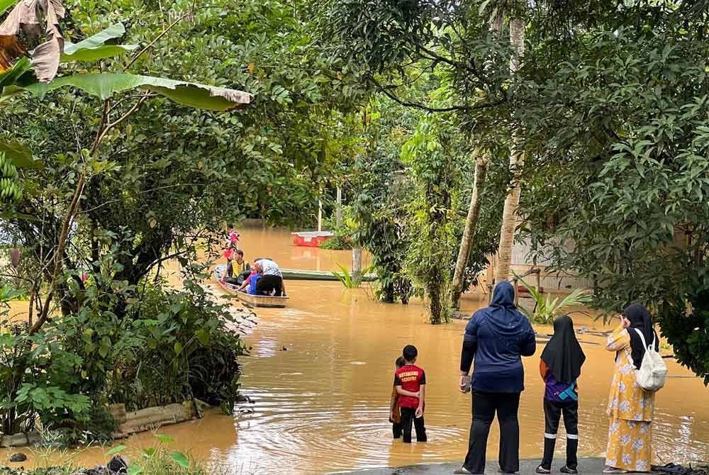 Penduduk pulang menyeberangi banjir di Limau Kasturi, Gua Musang.