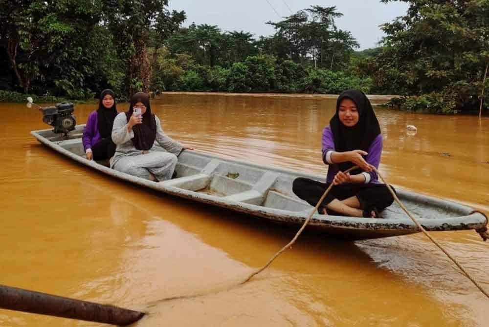 Penduduk menggunakan bot untuk keluar dari kawasan banjir di Gua Musang.
