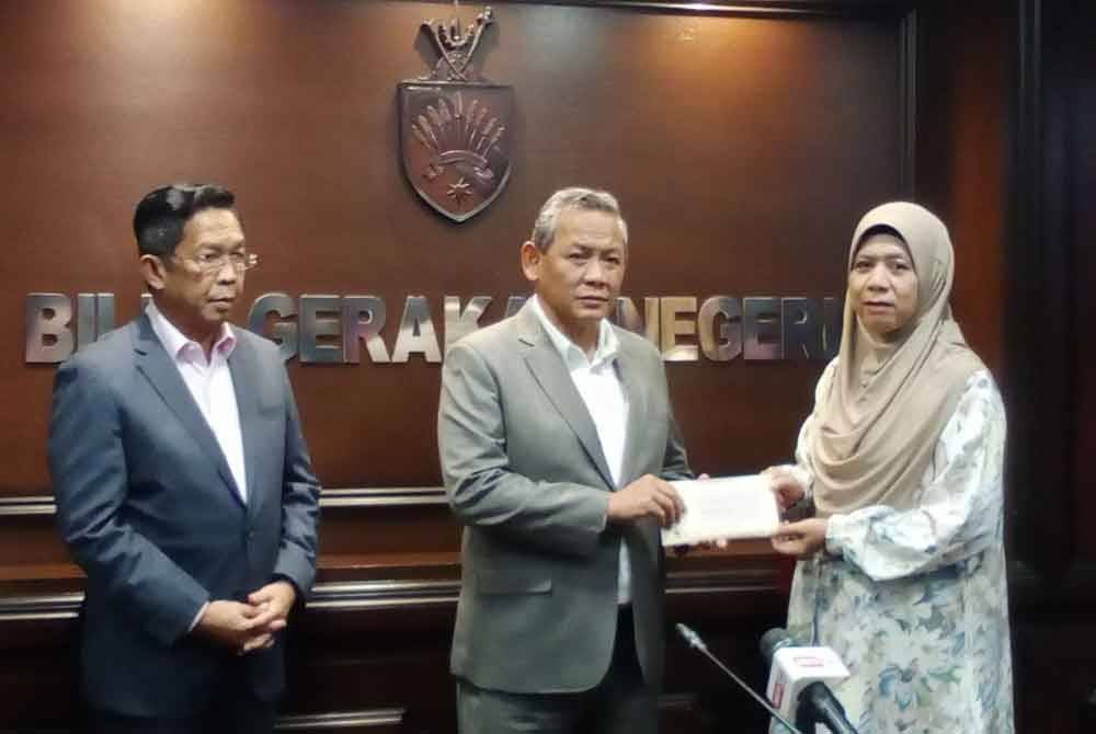 Aminuddin (tengah) menyampaikan sumbangan bantuan pengurusan jenazah kepada waris anggota JPKK Negeri Sembilan yang telah meninggal dunia, turut hadir Exco Kanan Negeri Sembilan, Datuk Seri Jalaluddin Alias (kiri).