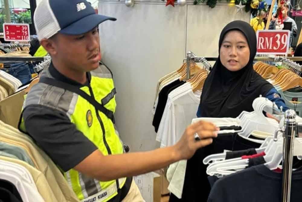 Penguat kuasa KPDN Kuala Lumpur sedang memeriksa pakaian jenama disyaki tiruan yang dijual di ruang legar sebuah pusat beli-belah, di sini, pada Isnin.