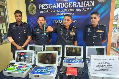 Mohamad Hatta (dua dari kanan) menunjukkan mesin judi yang dirampas