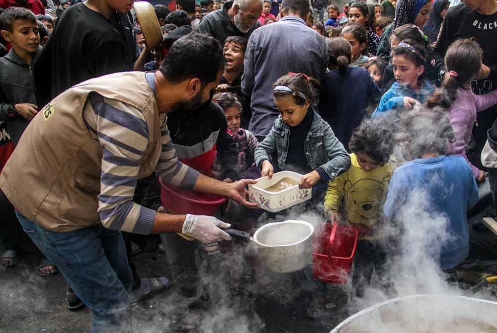Penduduk Palestin yang kehilangan tempat tinggal cuba mendapatkan bantuan makanan dari dapur komuniti tempatan di tengah-tengah kepungan yang dikenakan oleh tentera Israel dan kekurangan bantuan di kem Al-Shati. Foto Xinhua