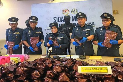 Raizam (tengah) menunjukkan bungkusan dadah jenia daun khat yang dirampas.
