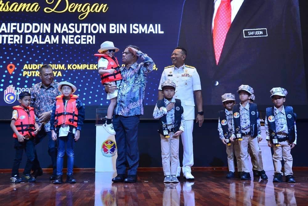 Saifuddin (empat dari kiri) mendukung seorang kanak-kanak ketika Perhimpunan Bulanan Kementerian Dalam Negeri.