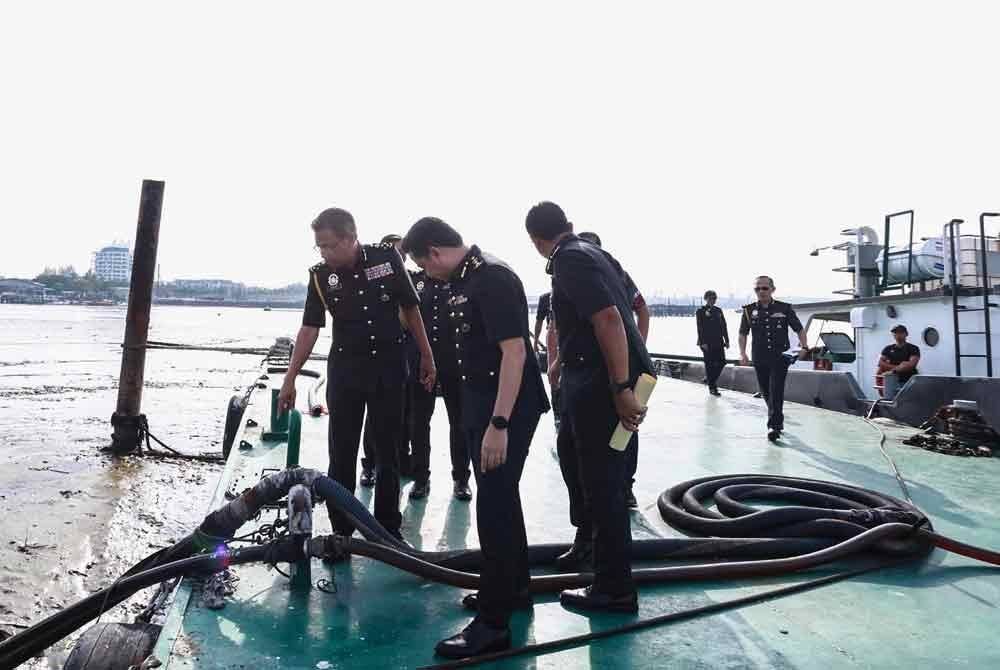 Azman (kiri) menunjukkan saluran penyambungan haram yang dibuat dari tangki kapal tunda untuk proses pemindahan diesel ke tangki minyak di perkampungan air Bagan Hailam, Pelabuhan Klang, Selangor.