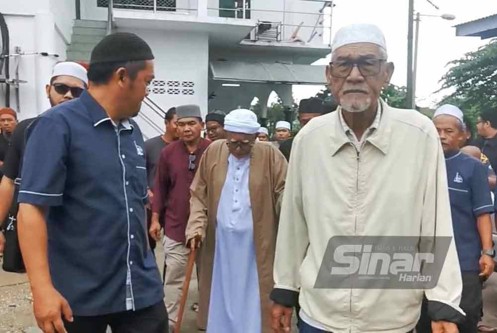 Abdul Hadi (tengah) dipimpin untuk kediamannya selepas selesai menyampaikan kuliah duha di Masjid Rusila di Marang pada Jumaat.