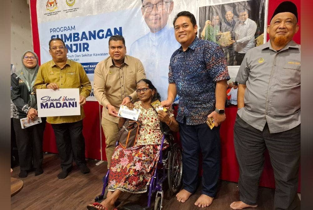 Mohamad Hairul Amir (dua dari kanan) dan Muhamad Arafat (tiga dari kiri) menyampaikan bantuan khas banjir kepada M Vijaylechumi, 57, dari Kampung Cheh.