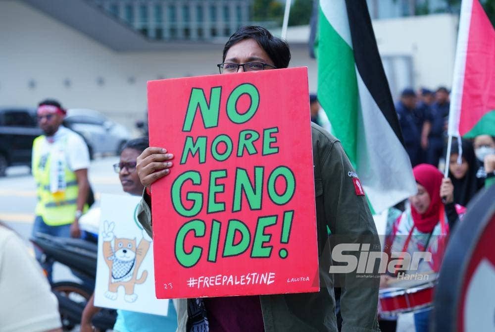 Salah seorang aktivis bersama sepanduk mengecam tindakan ganas Zionis. Foto Sinar Harian MOHD HALIM ABDUL WAHID