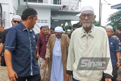 Abdul Hadi (tengah) dipimpin untuk kediamannya selepas selesai menyampaikan kuliah duha di Masjid Rusila di Marang pada Jumaat.
