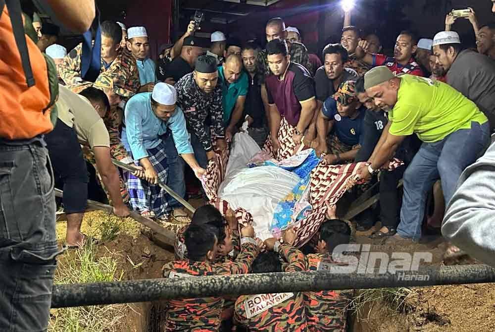 Penduduk turut membantu pihak bomba menurunkan jenazah ke liang lahad. - FOTO: SINAR HARIAN/ADILA SHARINNI WAHID.