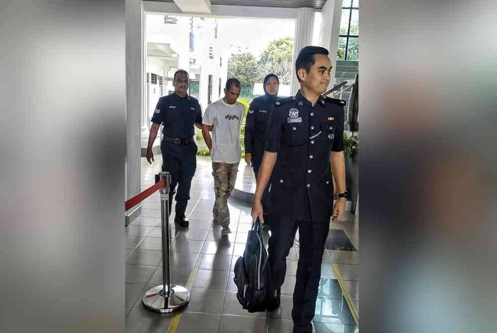 Musliadi belakang (dua dari kiri) ketika dibawa keluar dari Mahkamah Majistret di sini, pada Isnin.