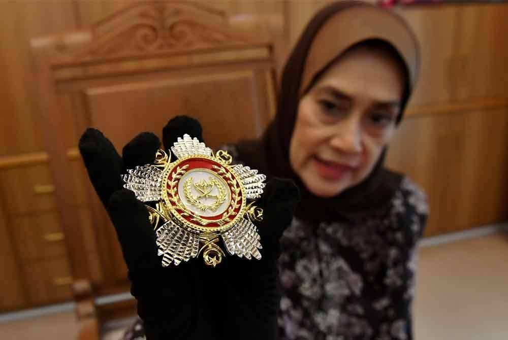 Putri Rafidah menunjukkan pingat darjah kebesaran negeri Pahang bersadurkan emas dan perak yang dihasilkan Mariwasa ketika ditemuramah di Kilang Mariwasa baru-baru ini. Foto Bernama