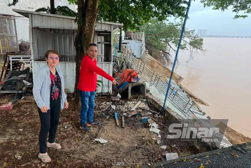 Mohd Razi (kanan) menunjukkan kesan runtuhan di tebing Sungai Kelantan di Kota Bharu pada Isnin. FOTO SINAR HARIAN-ADILA SHARINNI WAHID.