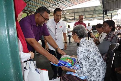 Haim Hilman (tengah) diiringi Raja Shahreen (tiga dari kiri) menyampaikan bantuan pasca banjir kepada para penerima di Masjid Sharifah Fatimah, Jitra. - Foto: BDB