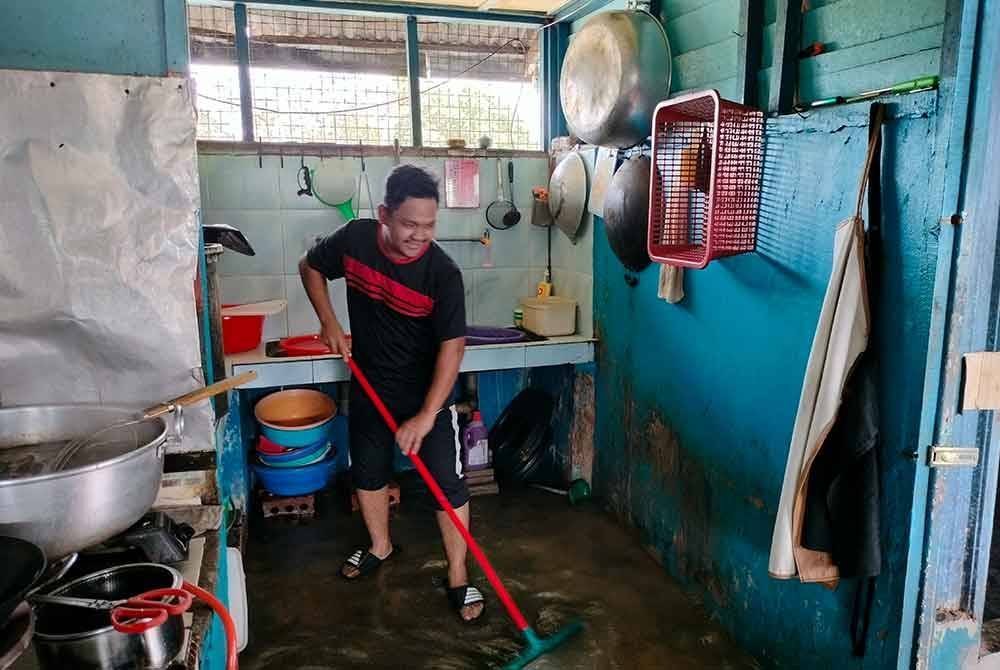 Pekerja Kedai Mi Udang di Rambah sedang membersihkan kedai selepas air pasang surut.