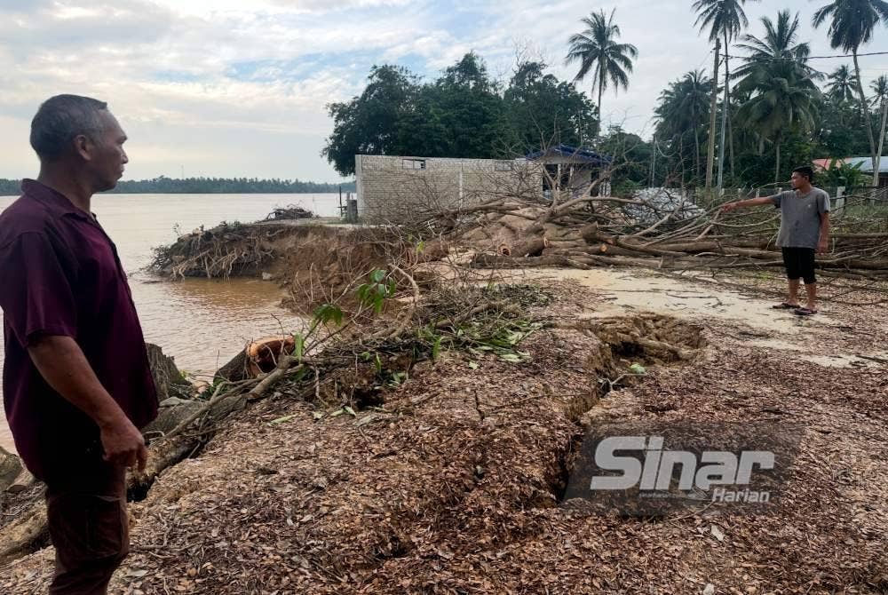 Mohd Nazrimi (kanan) menunjukkan runtuhan tebing Sungai Kelantan yang berlaku bermula 30 November lalu. Foto SINAR HARIAN ADILA SHARINNI WAHID 
