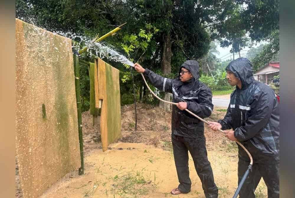Ahli KSPDN membantu membersihkan salah sebuah rumah mangsa banjir.