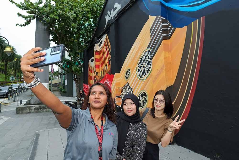  (Dari kiri) K.Kogila Devi, 40, Nur Fatin Mohmad Kadenan, 31, dan Yee Xiang Yun, 34, mengambil gambar lukisan mural yang terdapat di sekitar di Jalan Tan Hiok Nee yang juga dikenali sebagai "Jalan Warisan" hari ini.