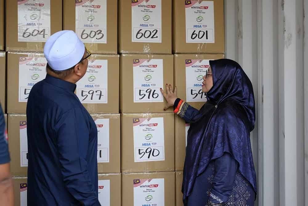 Pekerja Syria Care sedang menyusun lotak pakaian musim sejuk yang akan disumbangkan kepada pelarian Syria di Lubnan.