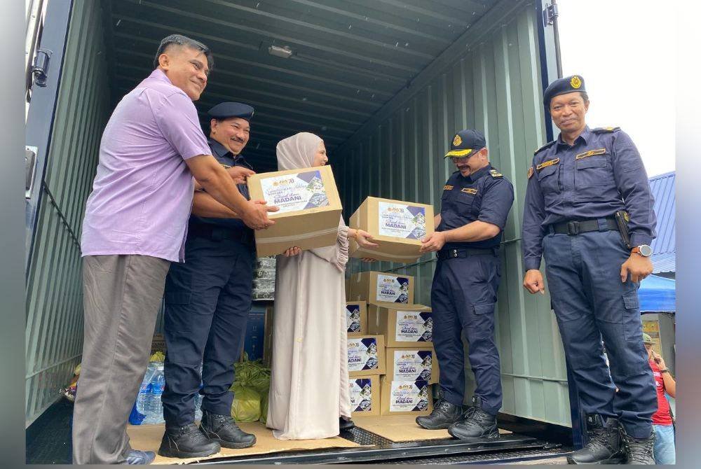 Muhammad Kifli (dua dari kiri) memeriksa barangan sumbangan yang akan diagihkan kepada mangsa banjir pada Program Sumbangan Bantuan Banjir oleh Skuad Ihsan Madani JPJ Malaysia di Kelantan.