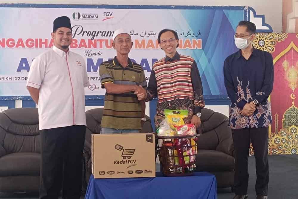 Ahmad Azrin (dua dari kanan) bergambar bersama penerima bantuan serta.Ilyas Helmi (kiri) pada Program Bantuan Makanan MAIDAM pada Ahad