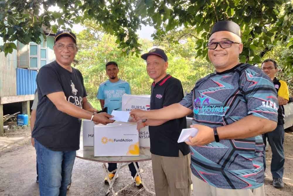 Mohd Zaidi (kiri) menerima bantuan yang disampaikan oleh Muhammad Nasir.