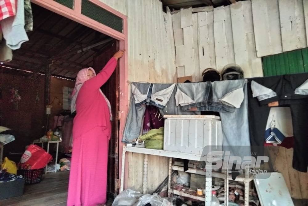 Norazila menunjukkan paras air banjir di rumahnya.