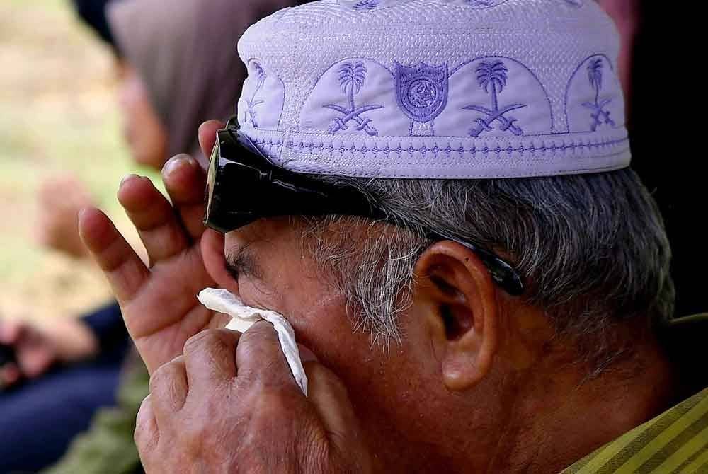 Bapa Allahyarham mengesat air mata ketika hadir mengiringi pengebumian mangsa.