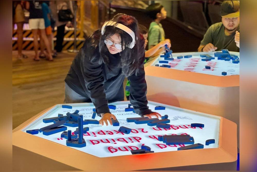 Pengunjung mencuba pameran interaktif di Petrosains 'The Discovery Centre'.